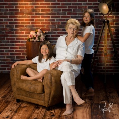 Portrait de famille au studio avec mamie et ses deux petites-filles, moment tendre et complice