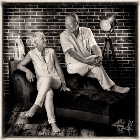Portrait de couple quinquagénaire en noir et blanc sur un canapé au studio, moment tendre et complice